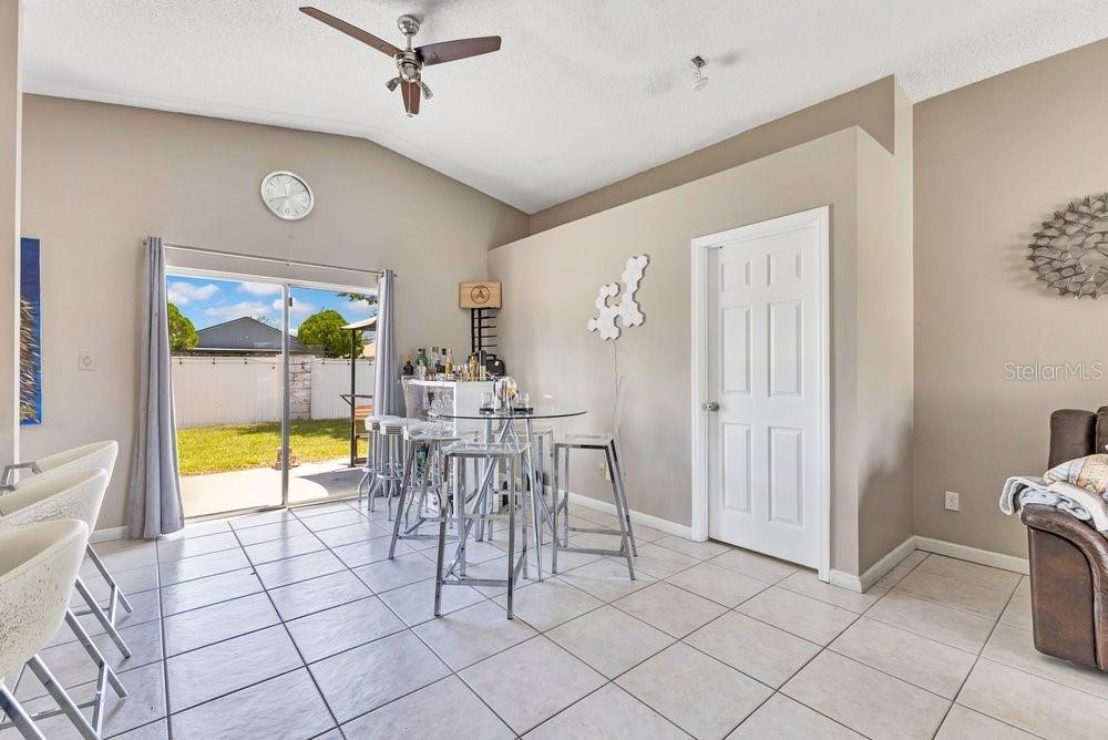 A dining area with a glass table, bar stools, tile flooring, and sliding glass doors — 3130 KOVAL COURT, ORLANDO, FL
