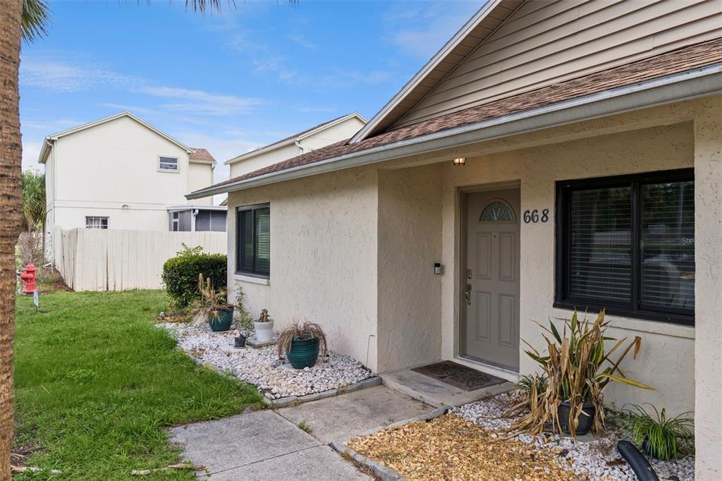 The exterior of a single-story home features a beige stucco facade and a front door — 668 OLYMPIC DRIVE UNIT 1, OCOEE, FL