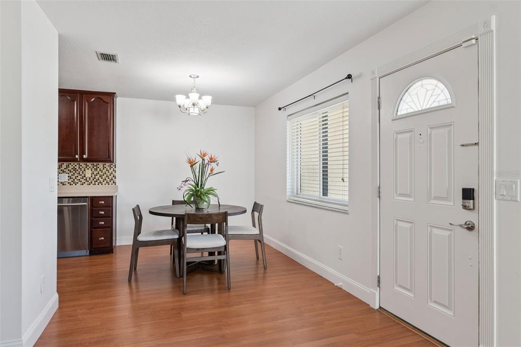 A dining area with a round table, chairs, wood flooring, and an adjacent kitchen — 668 OLYMPIC DRIVE UNIT 1, OCOEE, FL