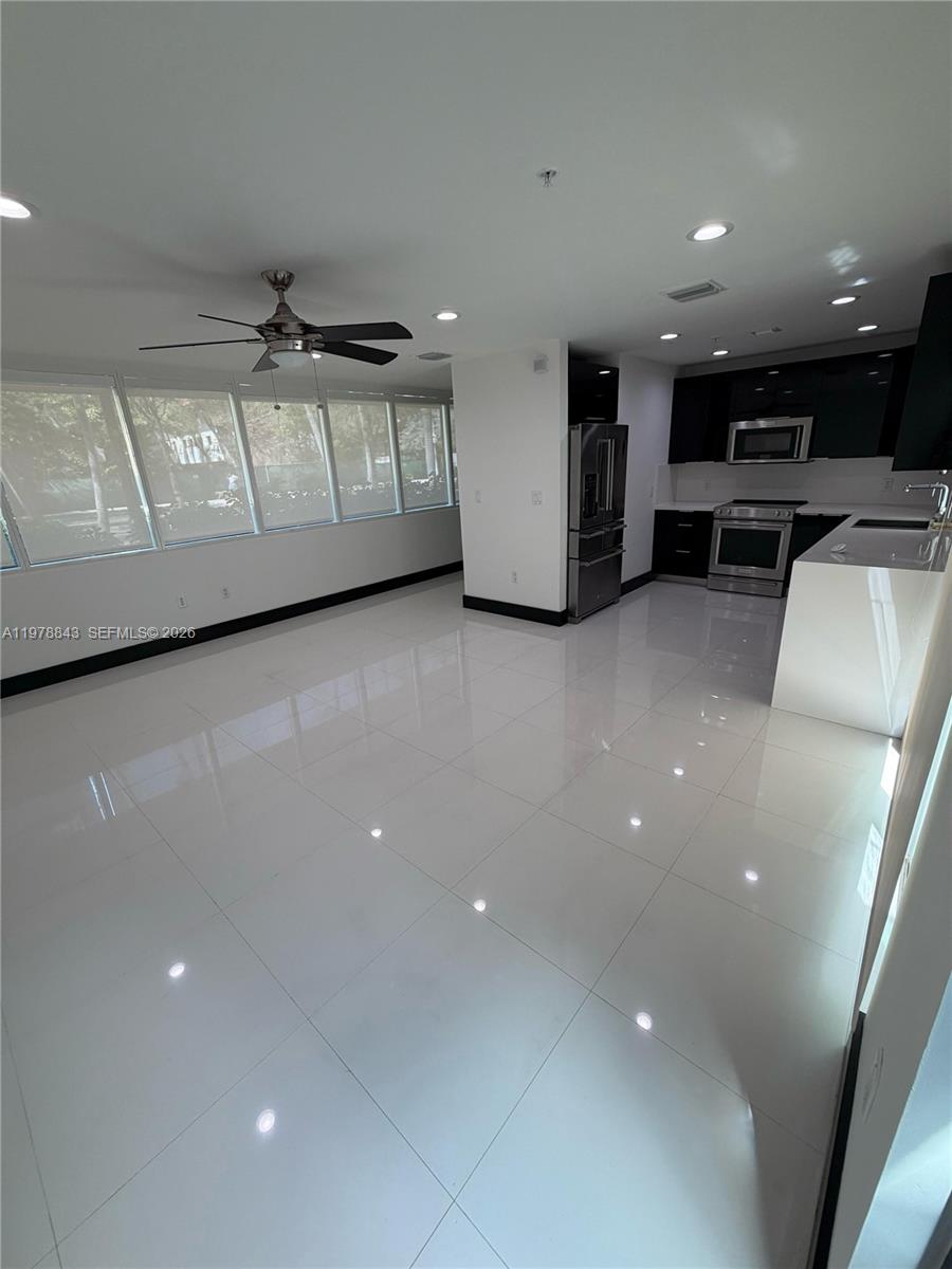 A modern kitchen with white tile floors opens into a living area with large windows — 2699 Tigertail Ave # 14, Miami FL 33133, MIAMI, FL