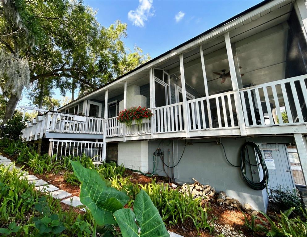 A raised house with a screened-in porch, white railings, and a garden in the foreground — 16533 LOWRY ROAD, MONTVERDE, FL