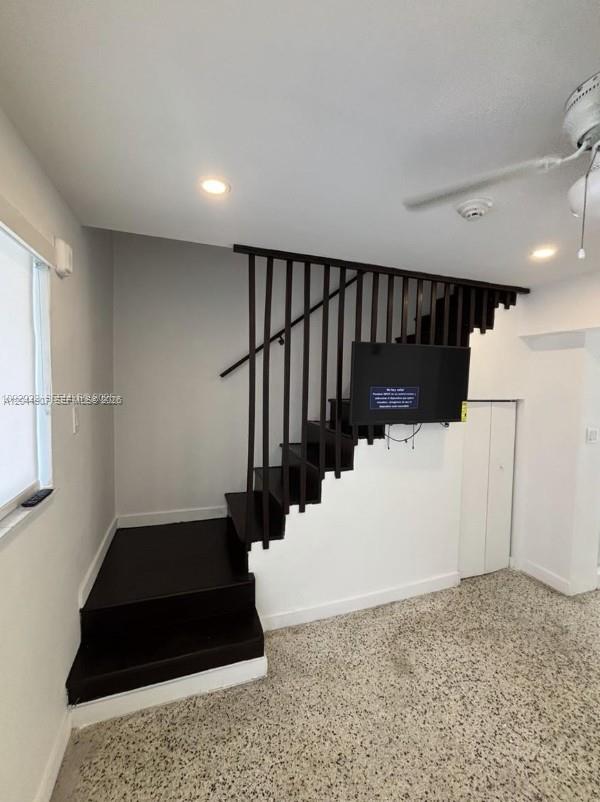 A room features a dark wooden staircase with vertical railings and a wall-mounted television — 560 NW 1st St # 7, Miami FL 33128, MIAMI, FL