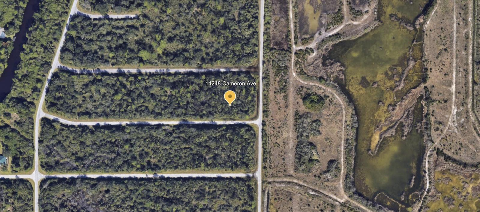 This aerial map view shows a wooded rectangular lot bordered by dirt roads and wetlands — 14248 Cameron Avenue, FL 33953, FL