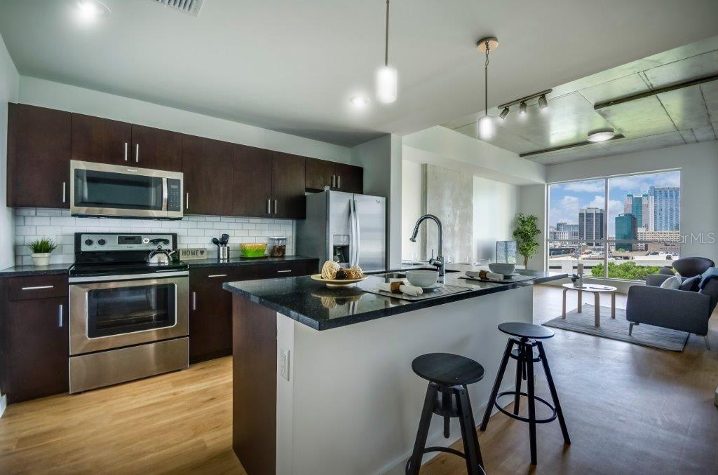 A modern kitchen with dark cabinets, stainless steel appliances, and an island overlooks a city view — 100-2 LAKE AVENUE, ORLANDO, FL