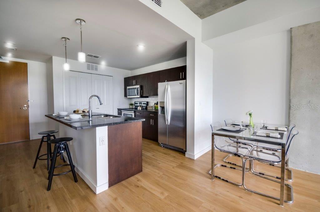 A modern kitchen with dark wood cabinets, stainless steel appliances, and an adjacent dining area — 100-2 LAKE AVENUE, ORLANDO, FL