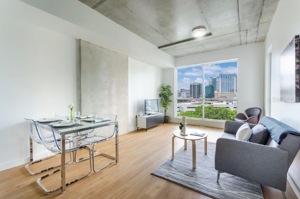 A modern living and dining area with concrete ceilings, light wood floors, and city views — 100-2 LAKE AVENUE, ORLANDO, FL