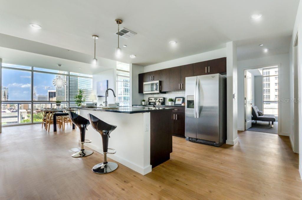 A modern kitchen with dark cabinetry, stainless steel appliances, and a breakfast bar island — 100-2 LAKE AVENUE, ORLANDO, FL