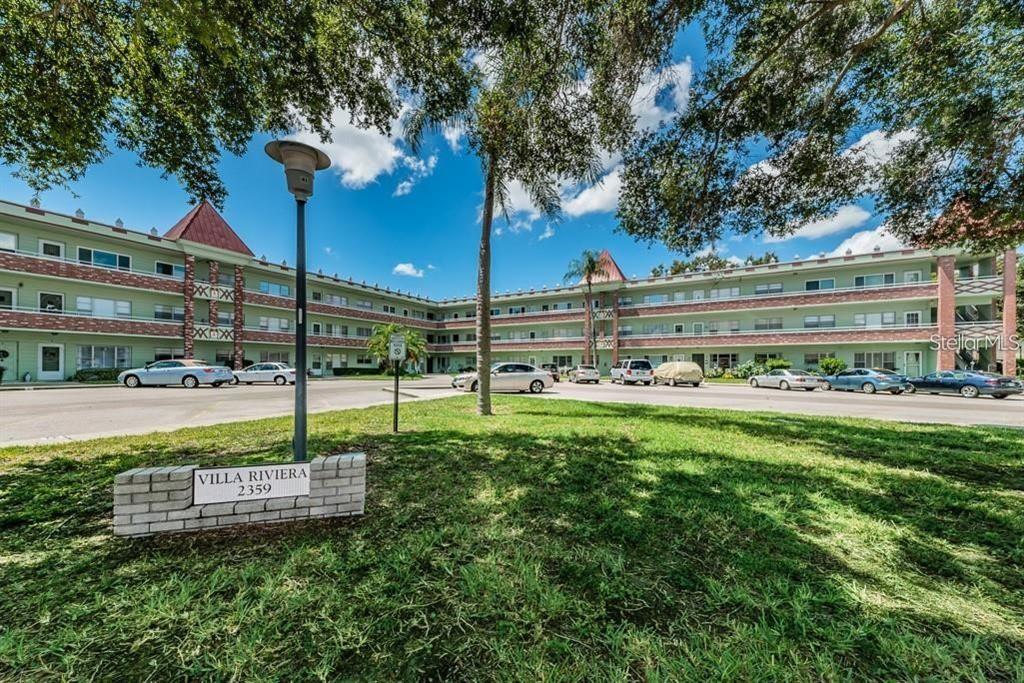 A three-story green apartment building with a brick sign in the foreground — 2359 FINLANDIA LANE UNIT 59, CLEARWATER, FL