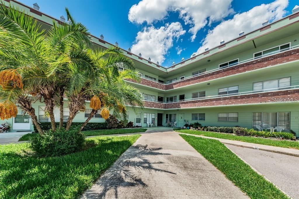 A three-story apartment building with a palm tree in the foreground and a concrete driveway — 2359 FINLANDIA LANE UNIT 59, CLEARWATER, FL