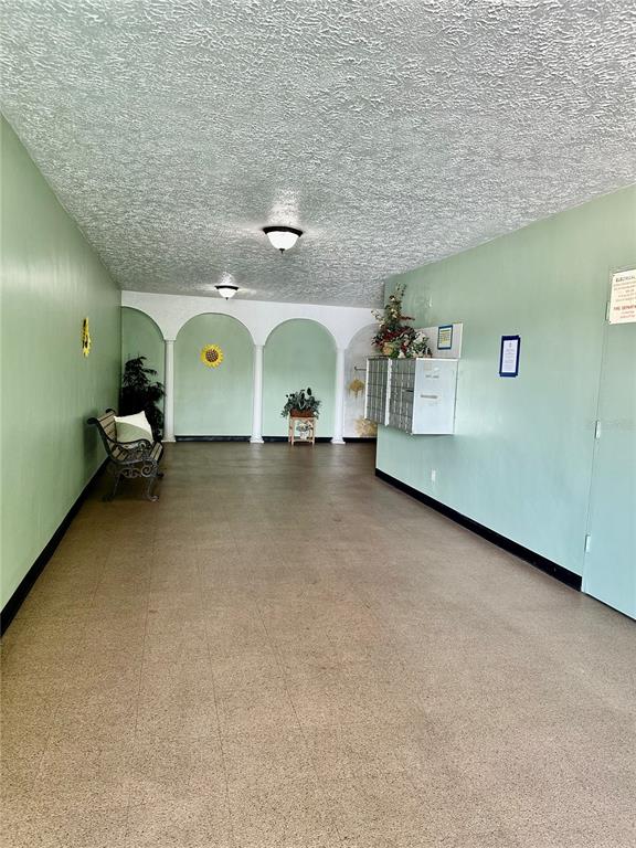 A hallway with light green walls, arched alcoves, a textured ceiling, and metal mailboxes — 2359 FINLANDIA LANE UNIT 59, CLEARWATER, FL
