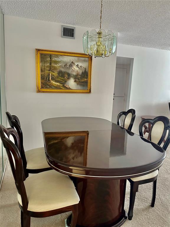 A dining room features a dark wood pedestal table, four upholstered chairs, and a chandelier — 2359 FINLANDIA LANE UNIT 59, CLEARWATER, FL