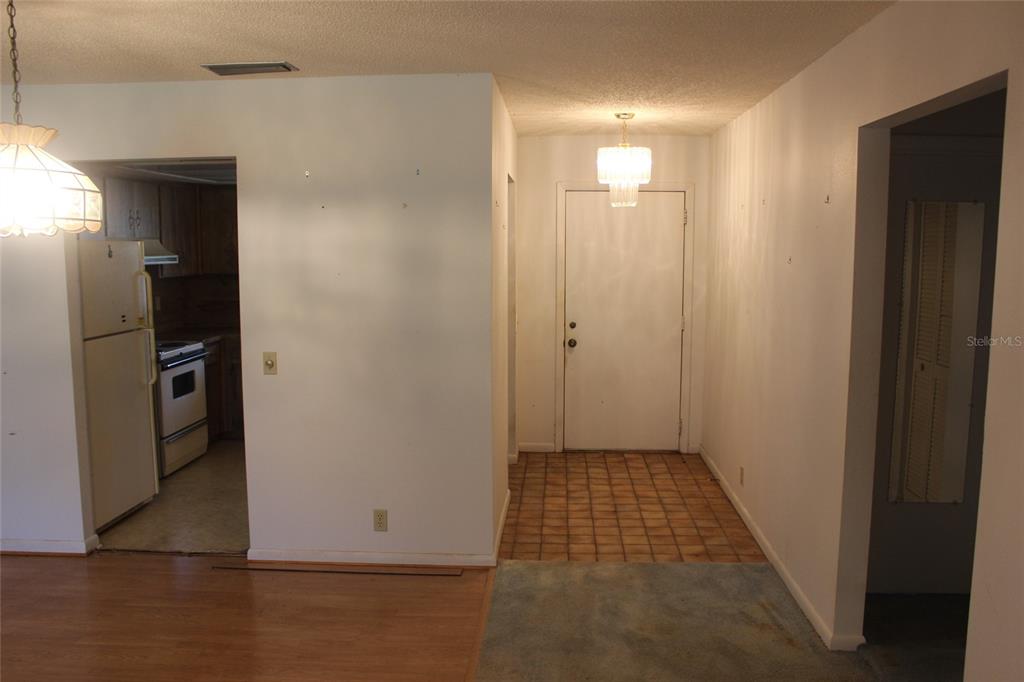 An interior view shows a kitchen, a tiled entryway with a front door, and carpeted flooring — 649 BROADMOOR CIRCLE, WINTER HAVEN, FL