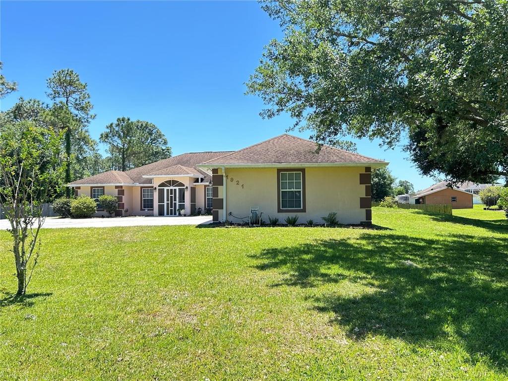 A single-story house with a tan exterior, brown trim, and a large front lawn — 1921 FLOWER TERRACE, SEBRING, FL