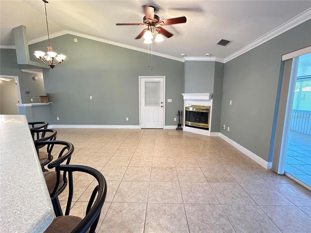 A spacious living room features tile flooring, a corner fireplace, and a vaulted ceiling — 1921 FLOWER TERRACE, SEBRING, FL