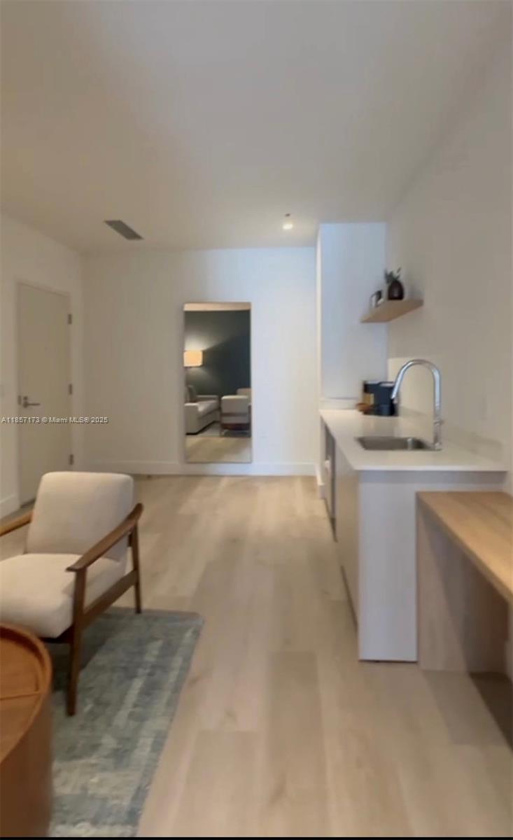This interior view shows a kitchen area with white cabinets, light wood flooring, and a mirror — 229 SW 9th St # 403, Miami FL 33130, MIAMI, FL