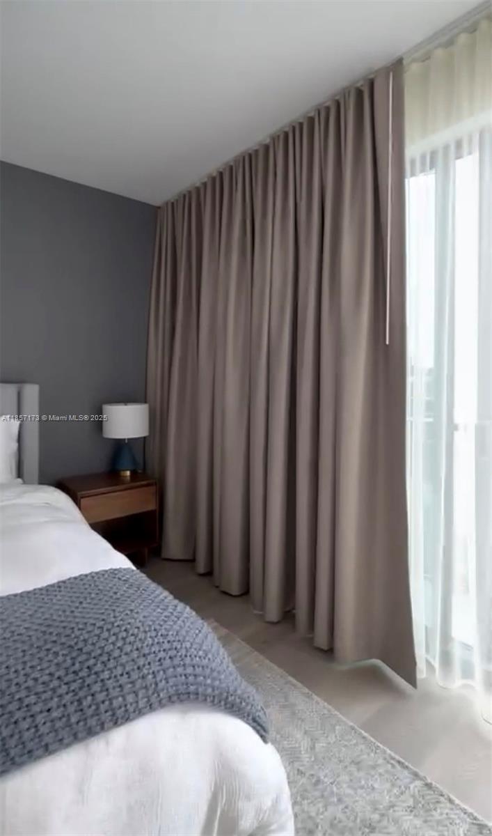 A bedroom features a bed, a wooden nightstand with a lamp, and floor-to-ceiling curtains — 229 SW 9th St # 403, Miami FL 33130, MIAMI, FL