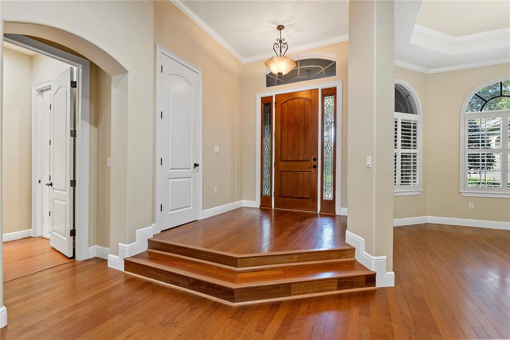 A foyer features a raised wooden platform leading to a front door with side lights — 8297 DAY LILY PLACE, SANFORD, FL