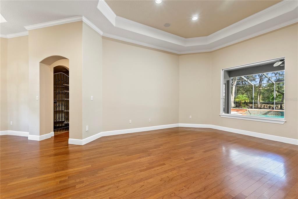 A spacious room with hardwood floors, a tray ceiling, and a view of a pool — 8297 DAY LILY PLACE, SANFORD, FL