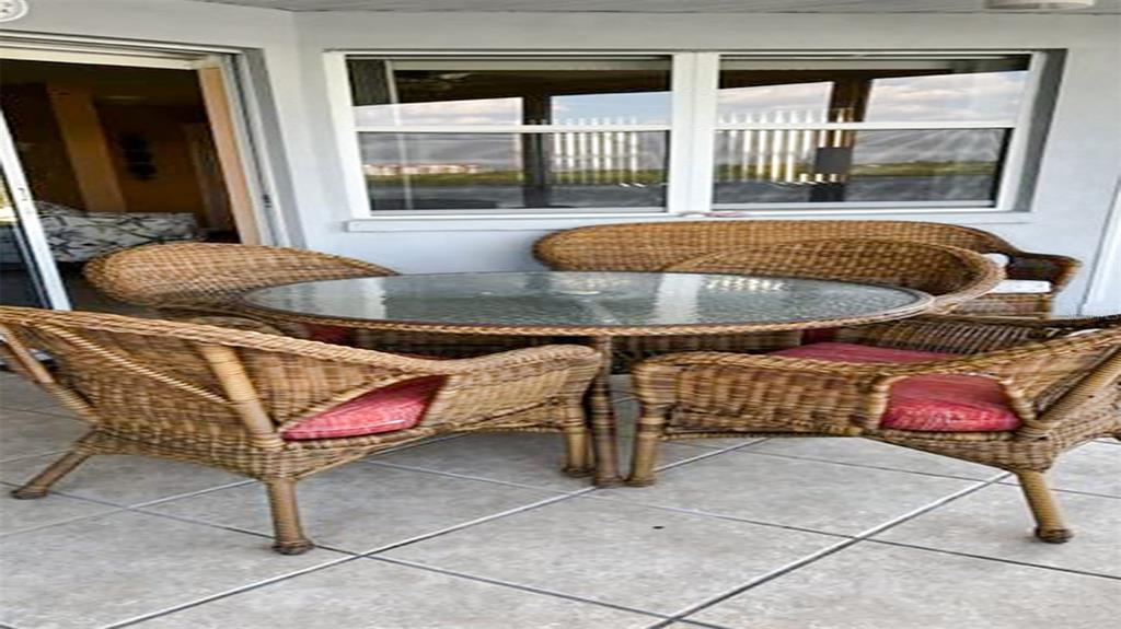 A patio features a glass-topped wicker table with four matching chairs on tiled flooring — 1365 SIESTA BAYSIDE DRIVE UNIT 1365-C, SARASOTA, FL