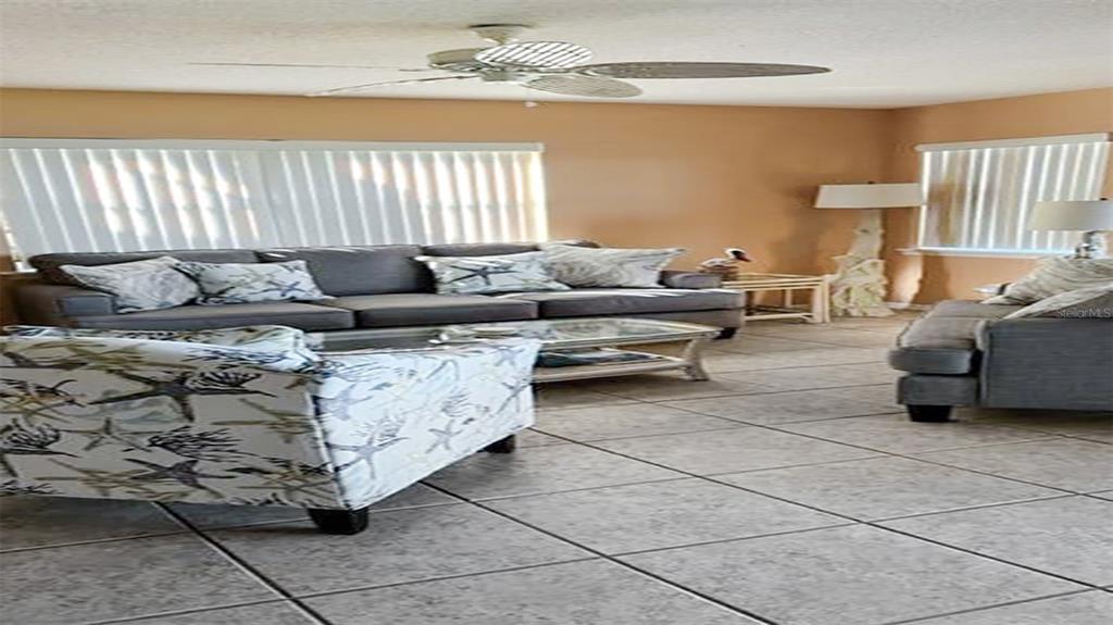 A living room features a gray sofa, a patterned armchair, and tile flooring — 1365 SIESTA BAYSIDE DRIVE UNIT 1365-C, SARASOTA, FL