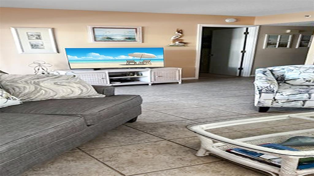 A living room features a gray sofa, a patterned armchair, and a television on a stand — 1365 SIESTA BAYSIDE DRIVE UNIT 1365-C, SARASOTA, FL