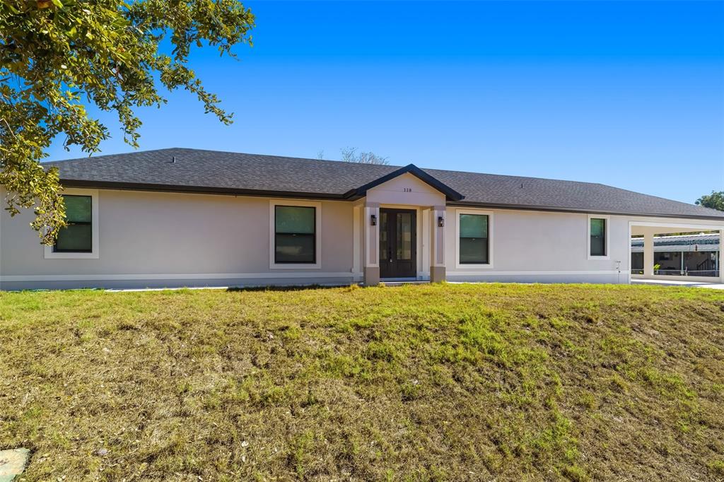 A single-story house with a light-colored exterior, dark roof, and a covered side carport — 118 RUBY AVENUE N, NOKOMIS, FL