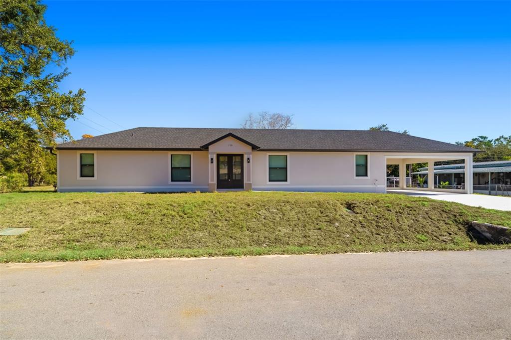A single-story house with a light-colored exterior, dark roof, and an attached carport — 118 RUBY AVENUE N, NOKOMIS, FL