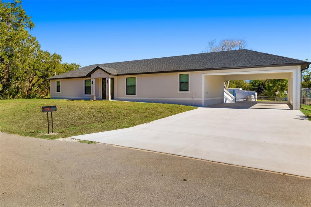 A single-story house with a light-colored exterior, a dark roof, and an attached carport — 118 RUBY AVENUE N, NOKOMIS, FL