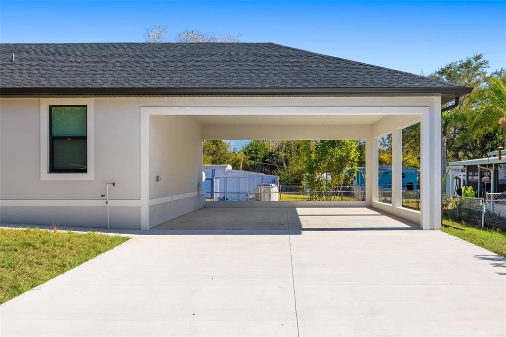 A concrete driveway leads to a covered carport attached to the side of a house — 118 RUBY AVENUE N, NOKOMIS, FL