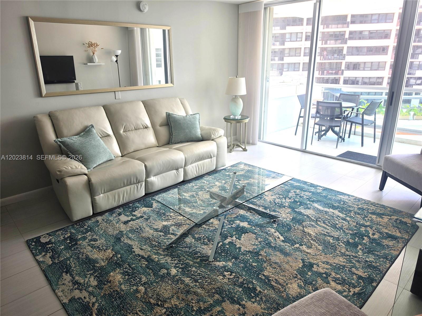 A living room features a cream leather sofa, a glass coffee table, and a blue rug — 5161 Collins Ave # 502, Miami Beach FL 33140, MIAMI BEACH, FL