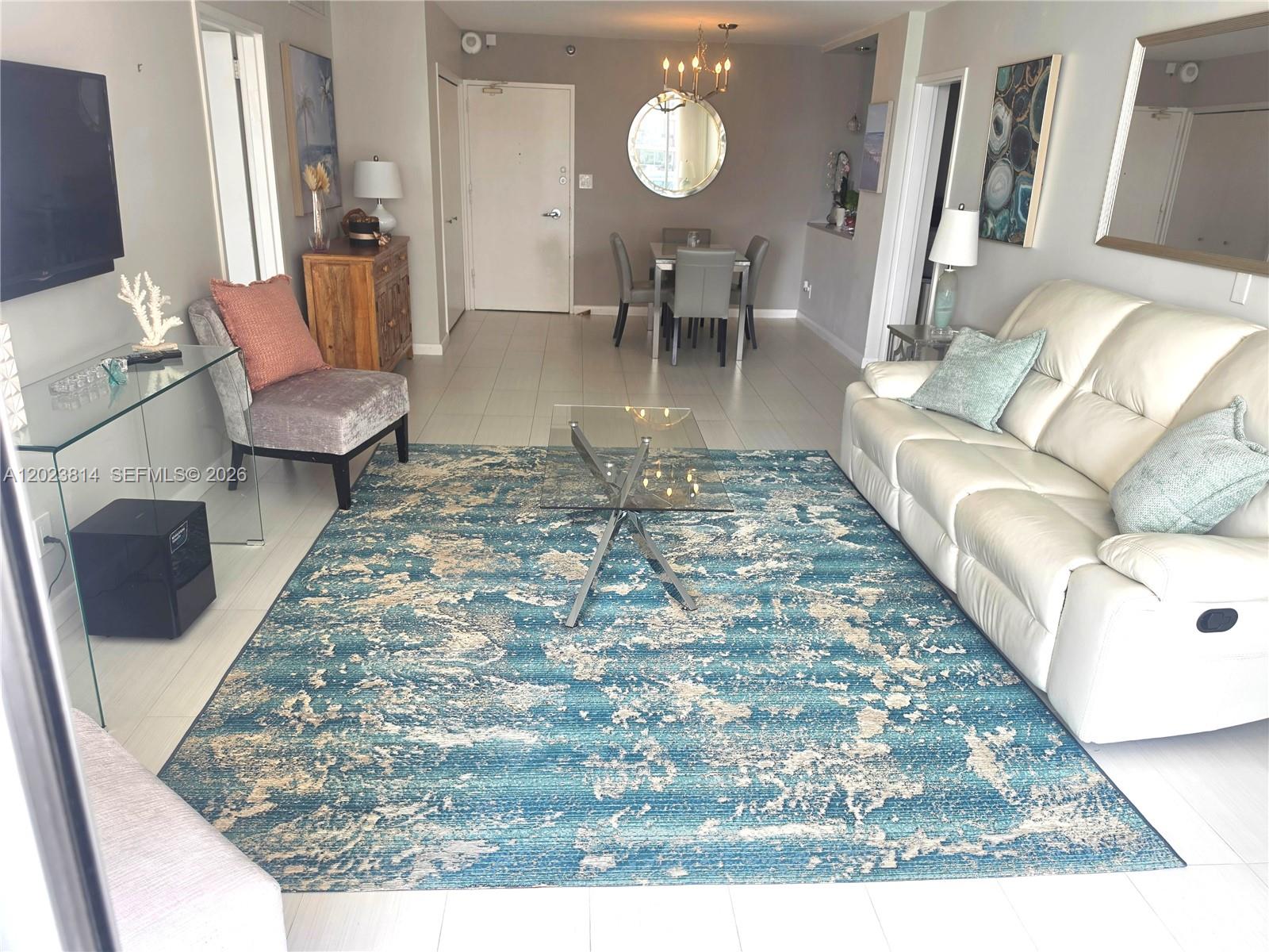 A living room features a large blue area rug, a white leather sofa, and glass tables — 5161 Collins Ave # 502, Miami Beach FL 33140, MIAMI BEACH, FL