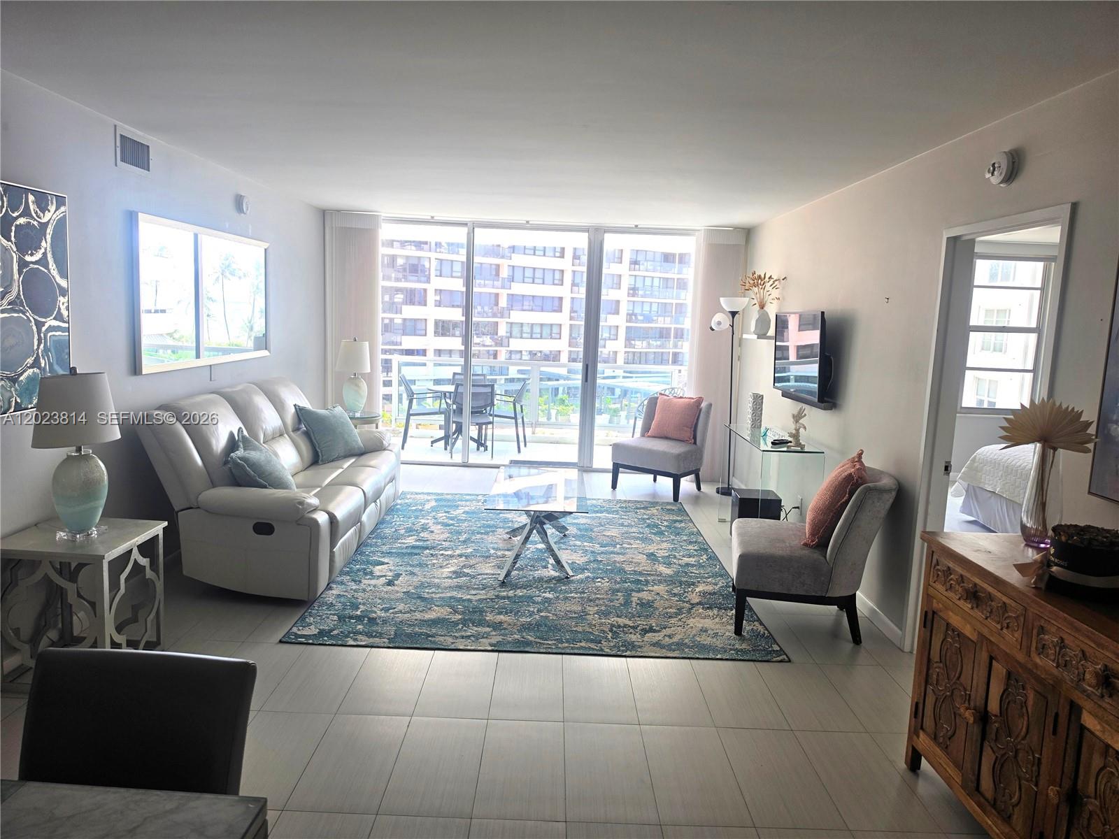 A living room features a white sofa, blue area rug, and balcony with outdoor seating — 5161 Collins Ave # 502, Miami Beach FL 33140, MIAMI BEACH, FL