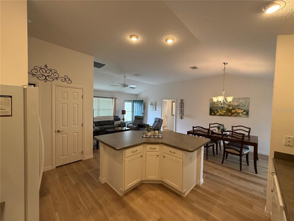 An open-concept kitchen with a central island overlooks a dining area and living room — 3135 BURNS DRIVE, THE VILLAGES, FL