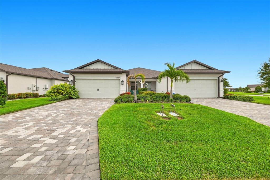 A single-story house with a three-car garage, a paved driveway, and a landscaped front lawn — 10208 COASTAL SHORES DRIVE, PARRISH, FL