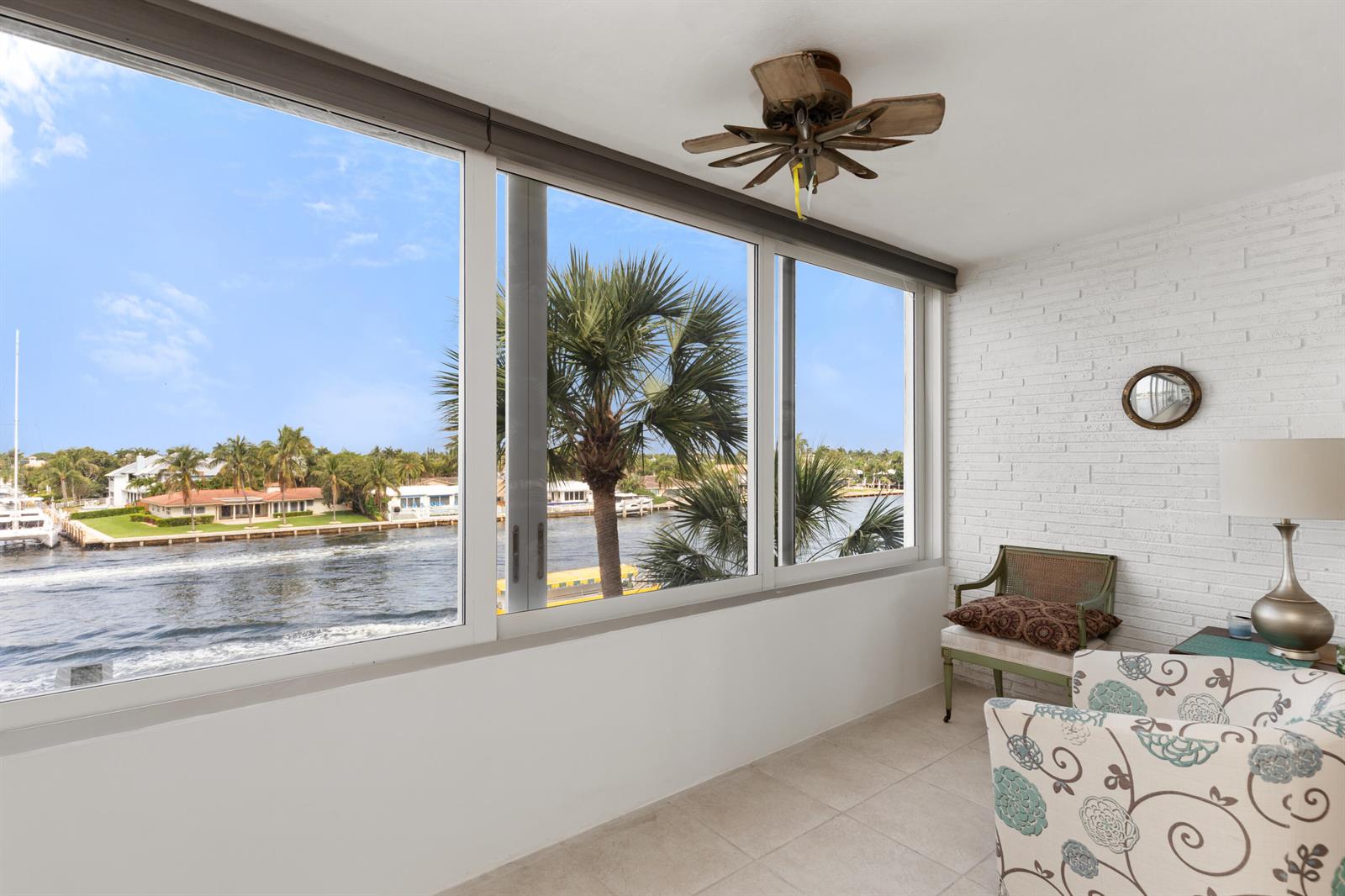 A sunroom with a white brick wall, tile floors, and large windows overlooking a waterway — 401 N Riverside Drive # 406, Pompano Beach FL 33062, POMPANO BEACH, FL