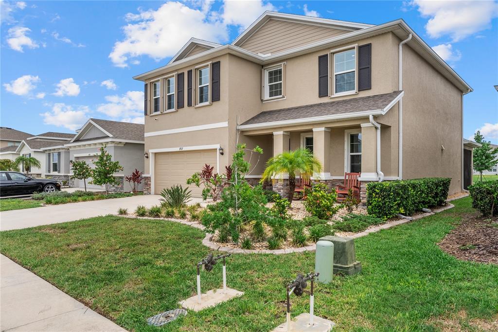 A two-story suburban house with a tan stucco exterior, a garage, and a front porch — 17727 CANTARINA COVE, BRADENTON, FL