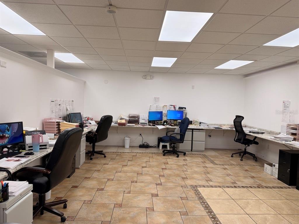 An office space features three workstations with computers, rolling chairs, and tiled flooring — 7117 N ARMENIA AVENUE, TAMPA, FL