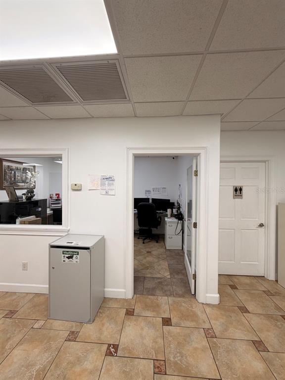 An office interior featuring a tiled floor, a shredding bin, a doorway, and a restroom door — 7117 N ARMENIA AVENUE, TAMPA, FL