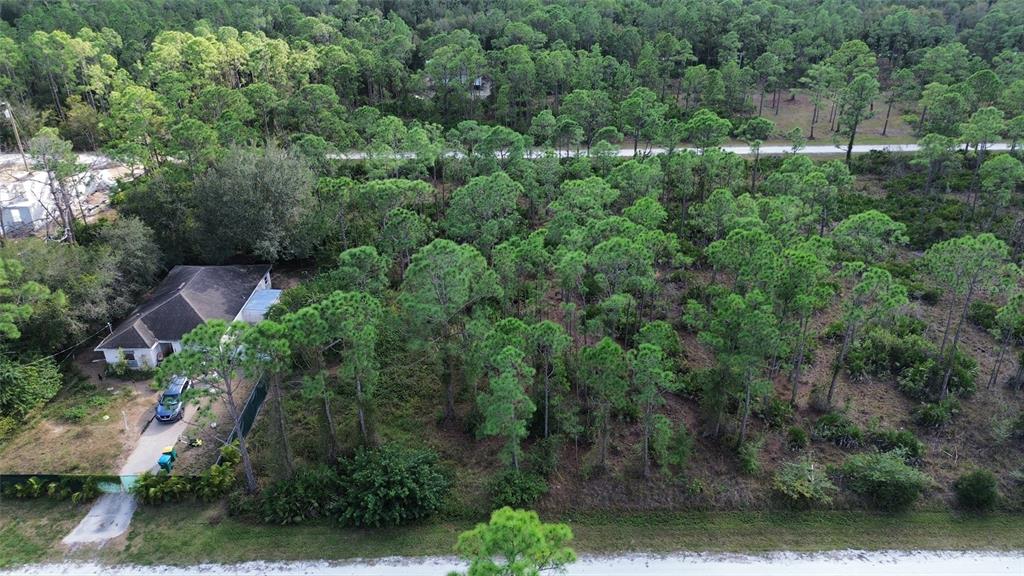 An aerial view shows a single-story house situated on a large, wooded lot — 28065 CRESTWOOD DRIVE, PUNTA GORDA, FL