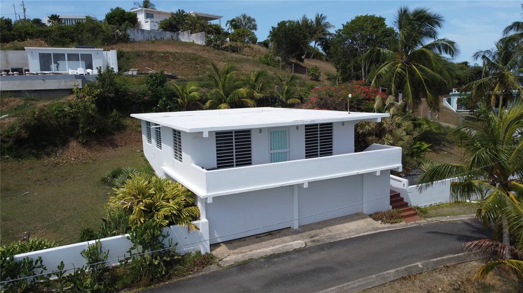 An elevated two-story white house with a balcony and a ground-level garage — 398 CASA CORAZON, VIEQUES, PR
