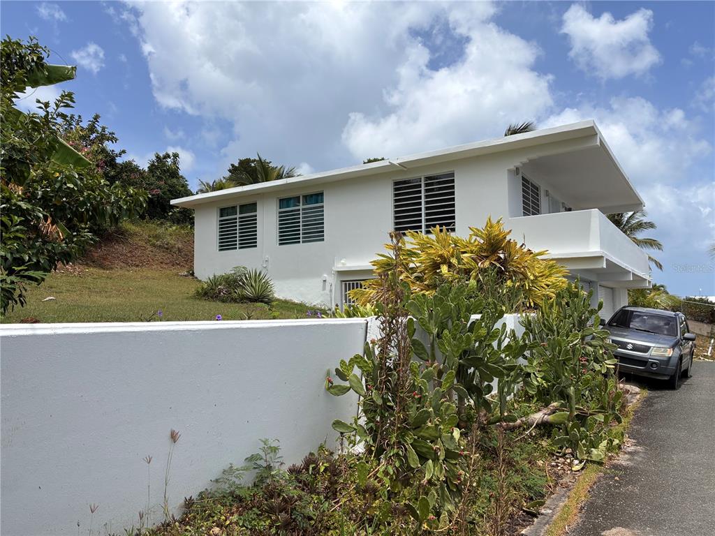 A white two-story house with louvered windows sits behind a low wall and cacti — 398 CASA CORAZON, VIEQUES, PR