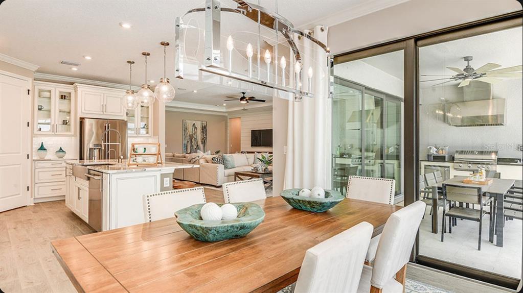 A dining area with a wooden table leads into a kitchen and an outdoor patio — 827 JUNONIA BOULEVARD, NEW SMYRNA BEACH, FL