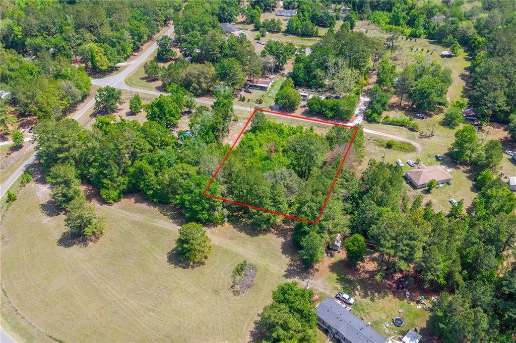 An aerial view shows a rectangular plot of land outlined in red amidst wooded surroundings — 5781 SW 91ST PLACE, LAKE BUTLER, FL