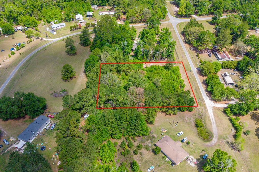 An aerial view shows a rectangular wooded lot outlined in red within a rural neighborhood — 5781 SW 91ST PLACE, LAKE BUTLER, FL