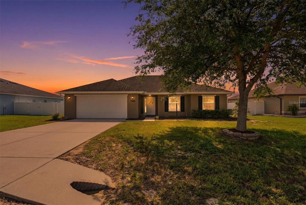 A single-story suburban house with a two-car garage and a large tree in front — 9917 SW 51ST COURT, OCALA, FL