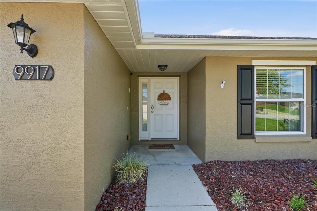 The exterior view shows a tan stucco home entrance with a white front door — 9917 SW 51ST COURT, OCALA, FL