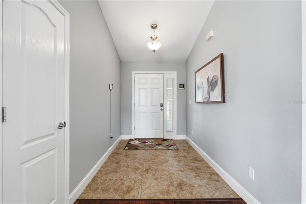 A bright entryway features light gray walls, tile flooring, a white front door, and lighting — 9917 SW 51ST COURT, OCALA, FL