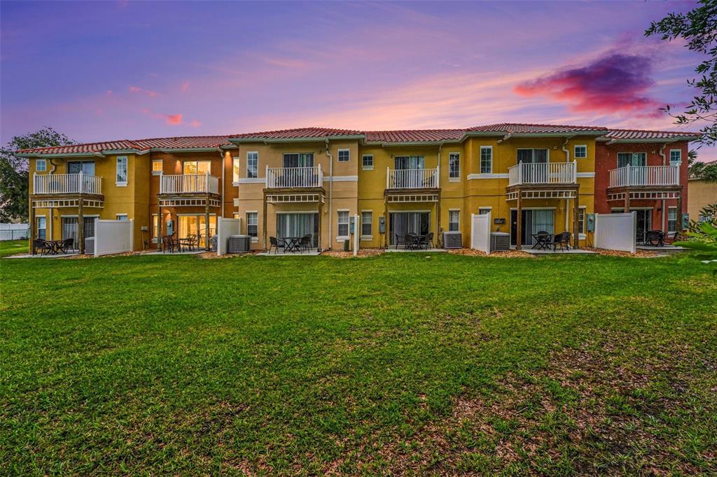 A multi-story apartment building with balconies and patios overlooks a large grassy lawn — 1081 PARK RIDGE CIRCLE, KISSIMMEE, FL