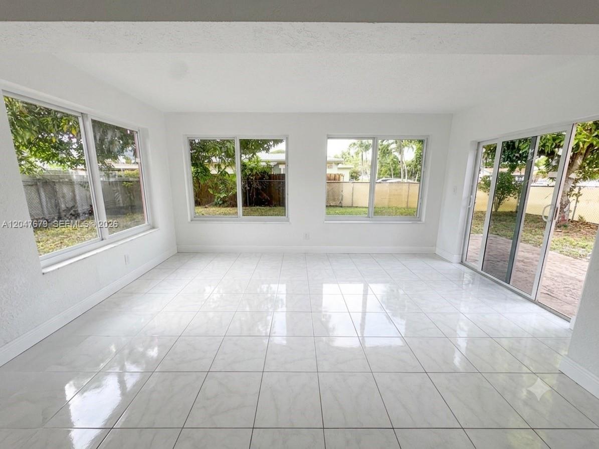 A bright sunroom features white tile flooring, large windows, and sliding glass doors — 7612 Plantation Blvd, Miramar FL 33023, MIRAMAR, FL