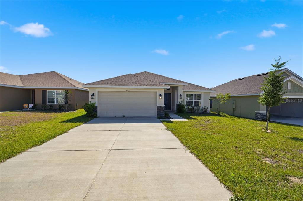 A single-story suburban house features a two-car garage, a concrete driveway, and a grassy lawn — 5524 OCEAN BREEZE DRIVE, SPRING HILL, FL